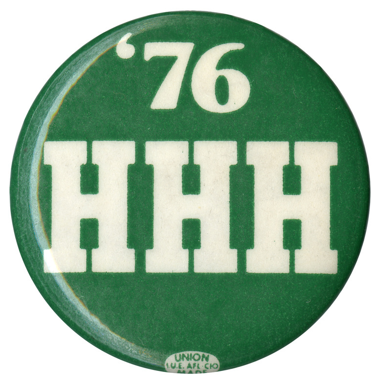 Round, green button with white text reading "'76 HHH"