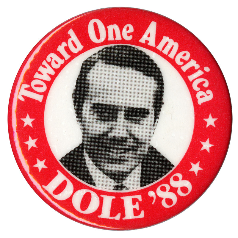 Round button with a red border and a black and white photograph of Bob Dole in the center. White text reads "Toward One America DOLE '88"