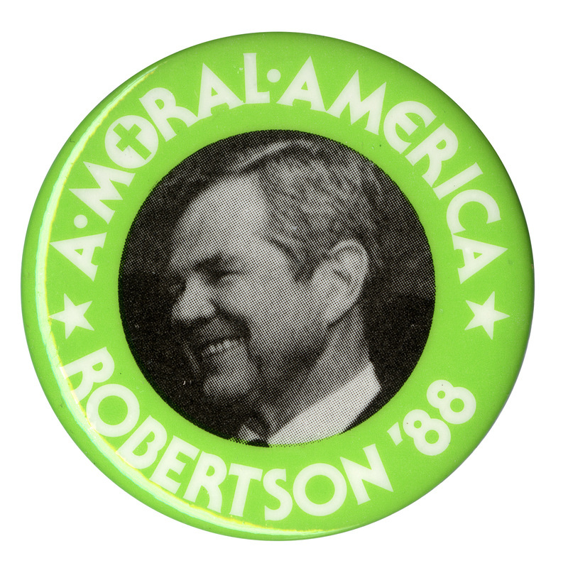 Round button with a green border and a black and white photograph of Pat Robertson in the center. White text reads "A MORAL AMERICA ROBERTSON '88". The "O" in "MORAL" contains a Christian cross.