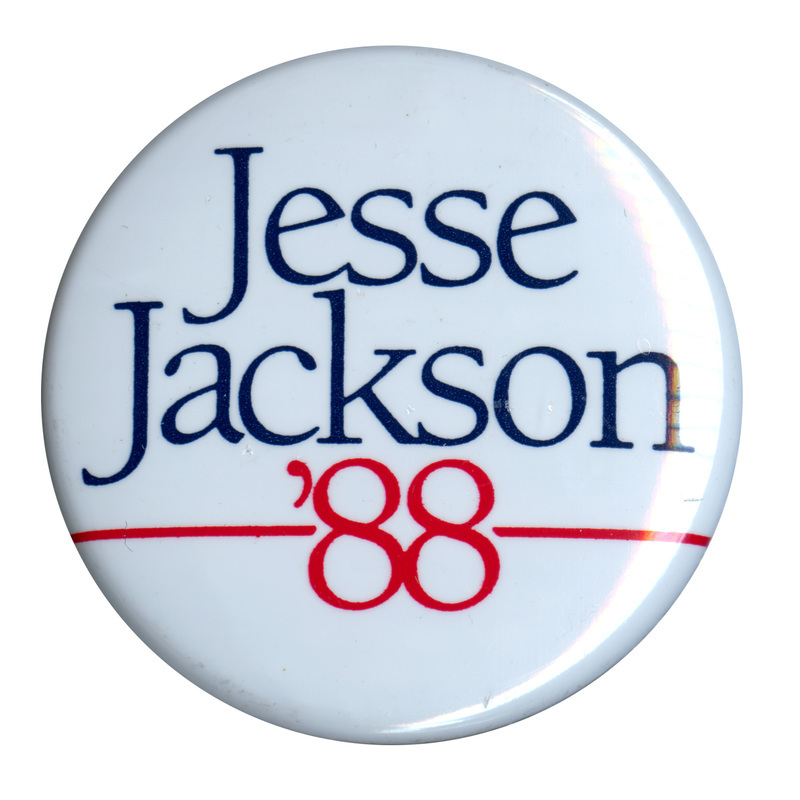Round, white button with blue and red text reading "Jesse Jackson '88"