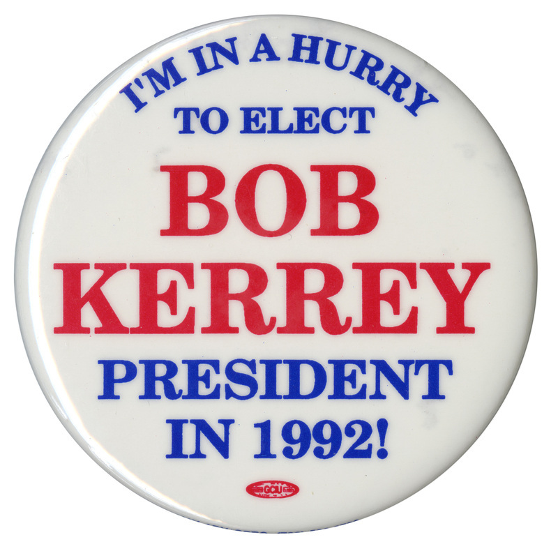 Round, white button with blue and red text reading "I'M IN A HURRY TO ELECT BOB KERREY PRESIDENT IN 1992!"