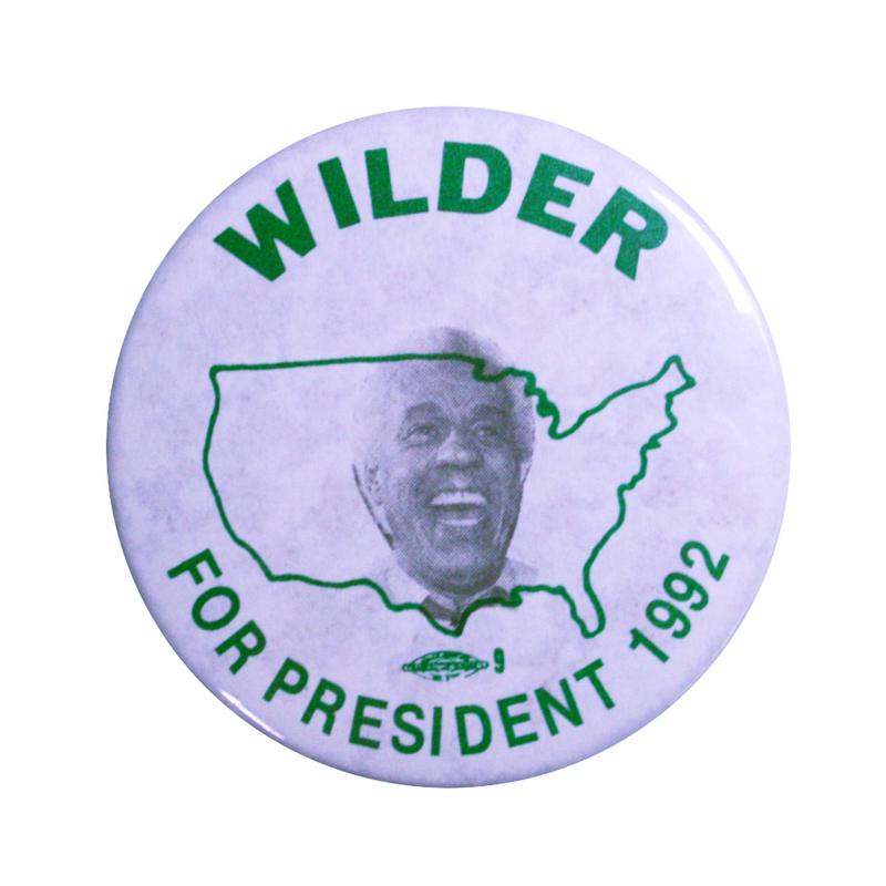 Round, grayish button with a black and white photograph of Lawrence Douglas Wilder against a black outline of the United States. Black text reads "WILDER FOR PRESIDENT 1992"