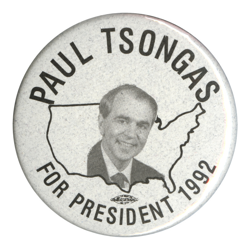 Round, gray button with a black and white photograph of Paul Tsongas against a black outline of the United States. Black text reads "PAUL TSONGAS FOR PRESIDENT 1992"