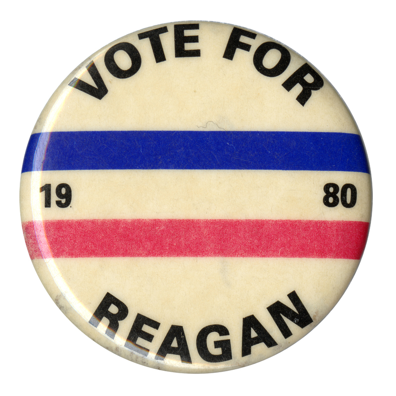 Round, white button with bands of red and blue. Black text reads "VOTE FOR 1980 REAGAN"