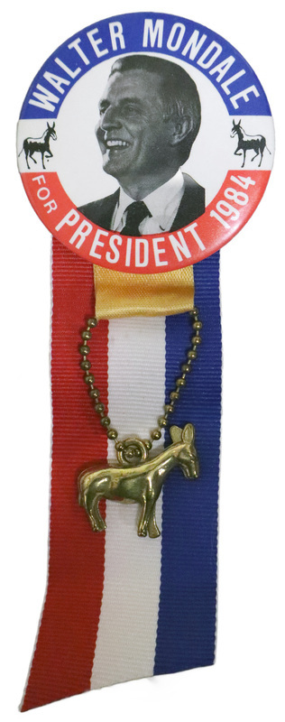 Round button with a red and blue border and a black and white photograph of Walter Mondale flanked by drawings of two black donkeys. White text reads "WALTER MONDALE FOR PRESIDENT 1984." Attached to the bottom of the button is a red, white, and blue ribbon and a gold donkey charm.