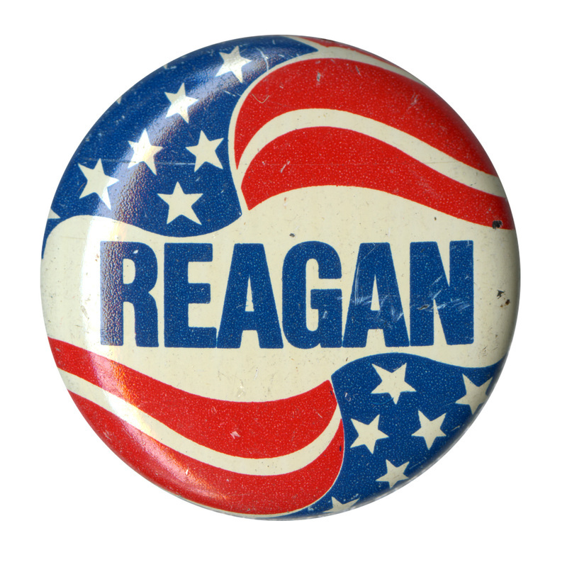 Round button with red, white, and blue stars and stripes decoration and blue text reading "REAGAN"