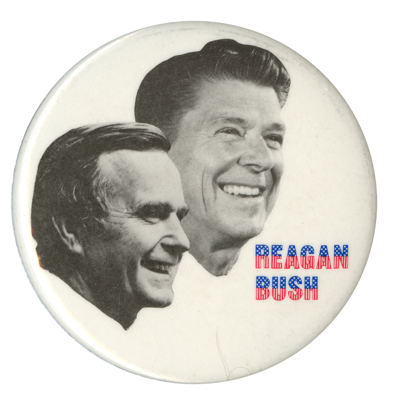 Round, white button with black and white photographs of George H. W. Bush and Ronald Reagan. Red and blue text reads "REAGAN BUSH"