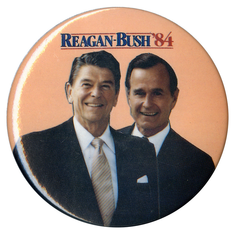 Round, orange button with color photographs of Ronald Reagan and George H. W. Bush. Blue and red text reads "REAGAN-BUSH '84"