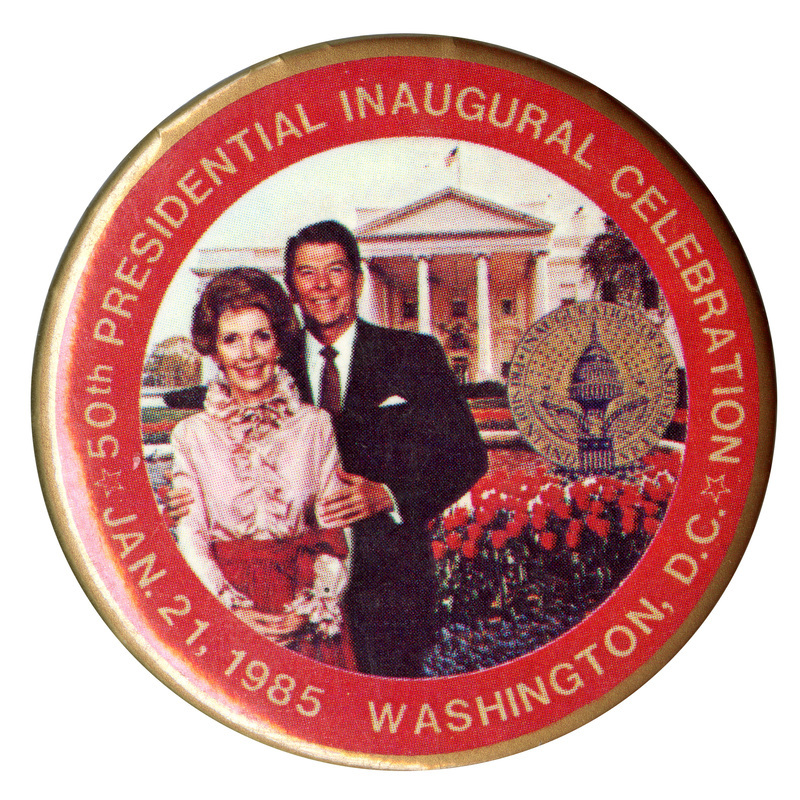 Round button with a red border and a color photograph of Nancy and Ronald Reagan with the White House, a seal, and flowers in the background. Gold text reads "50th PRESIDENTIAL INAUGURAL CELEBRATION JAN. 21, 1985 WASHINGTON, D.C."