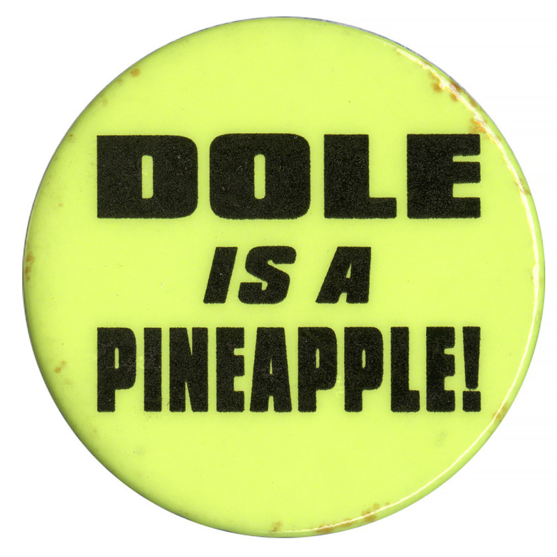 Round, neon green button with black text reading "DOLE IS A PINEAPPLE!"
