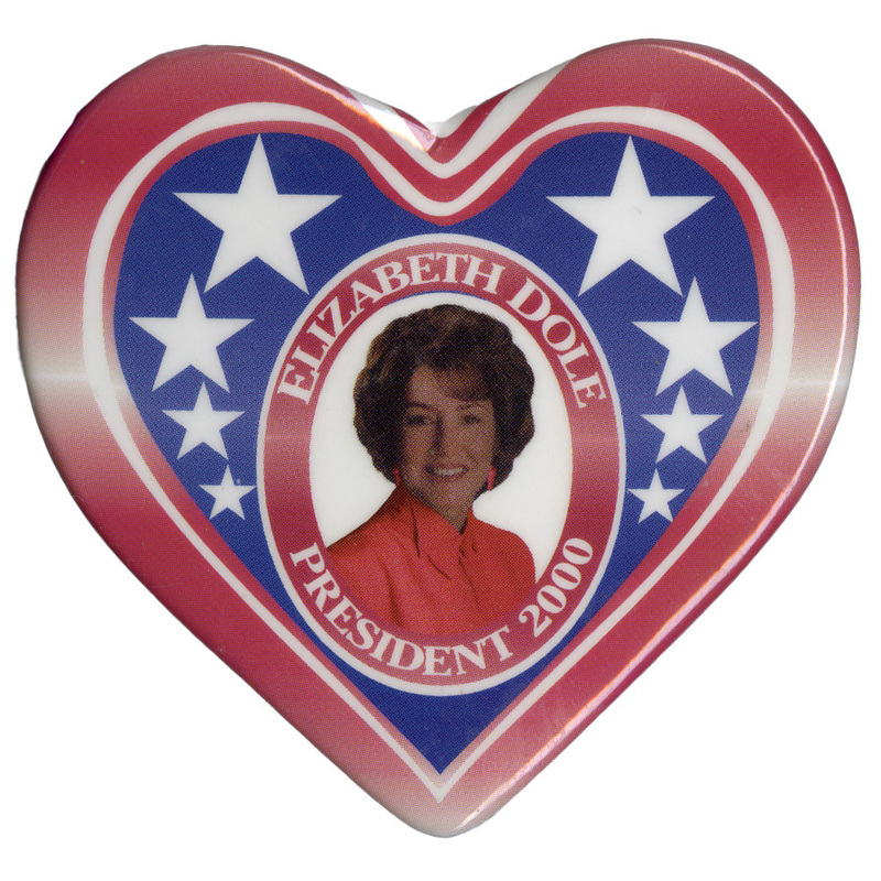 Heart-shaped button with a red and white striped border around a section of blue with white stars. In the center is a color photograph of Elizabeth Dole. White text reads "ELIZABETH DOLE PRESIDENT 2000"