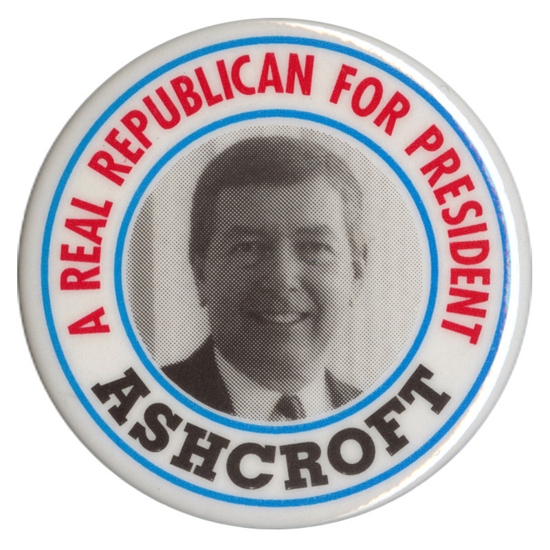 Round, white button with a black and white photograph of John Ashcroft in the center. Red and black text reads "A REAL REPUBLICAN FOR PRESIDENT ASHCROFT"