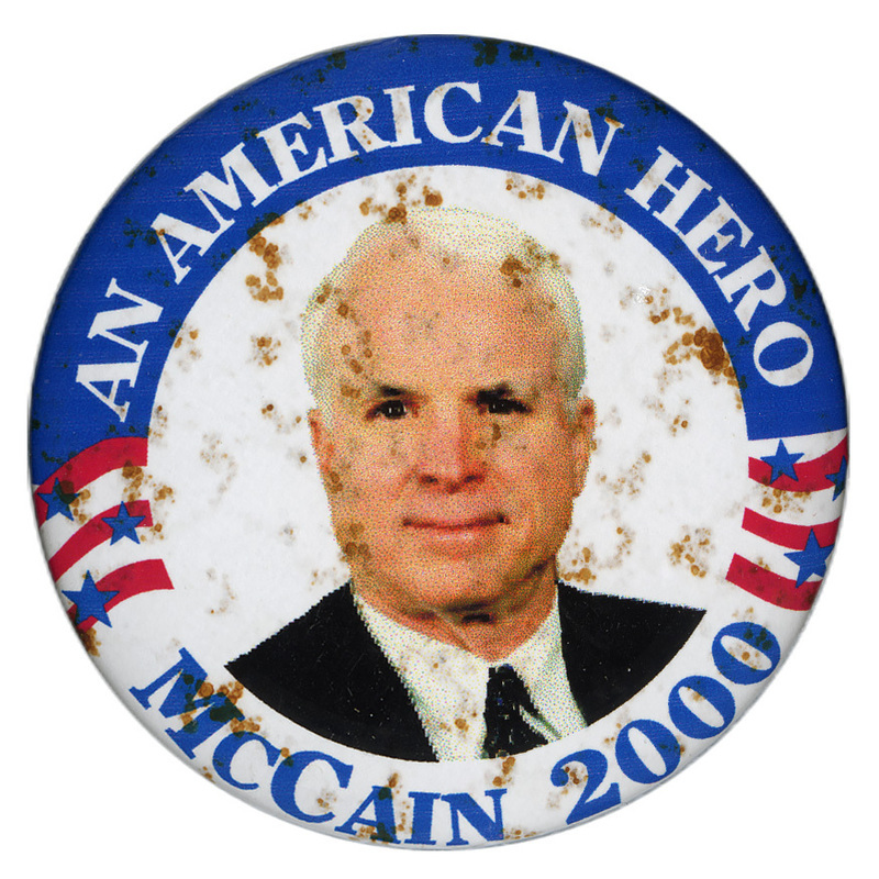 Round button with a red, white, and blue border. In the center is a color photograph of John McCain. White and blue text reads "AN AMERICAN HERO MCCAIN 2000"