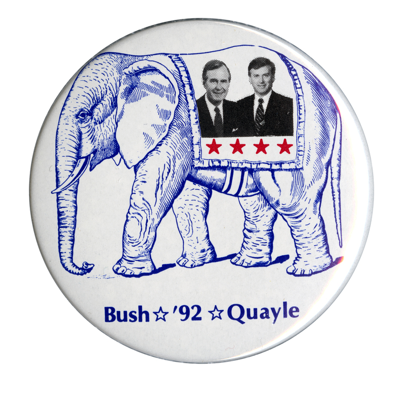 Round, white button with a blue drawing of an elephant wearing a blanket that has black and white photographs of George H. W. Bush and Dan Quayle above four red stars. Blue text reads "Bush '92 Quayle"