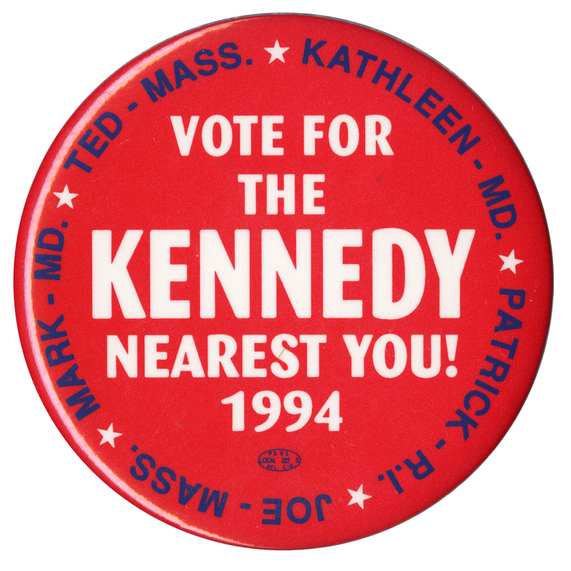 Round, red button with white text in the center reading "VOTE FOR THE KENNEDY NEAREST YOU! 1994" Blue text around the edge of the button reads "KATHLEEN - MD. PATRICK R. I. JOE - MASS. MARK - MD. TED - MASS."