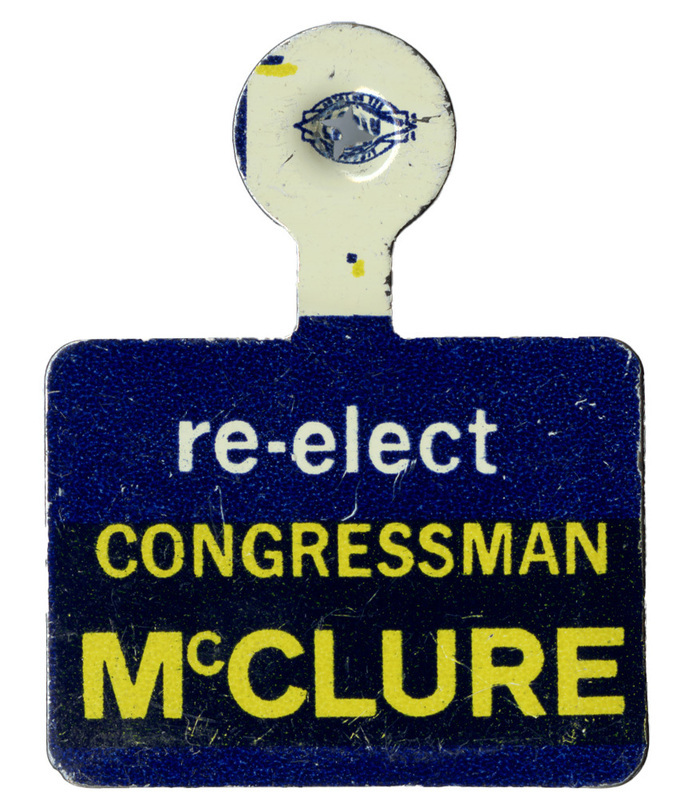 Blue, fold over lapel pin with white and yellow text reading "re-elect CONGRESSMAN McCLURE"