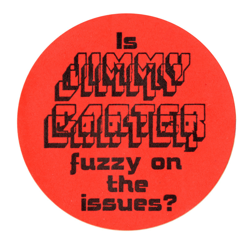 Round, orange sticker with black text reading "Is JIMMY CARTER fuzzy on the issues?" The words "JIMMY CARTER" are intentionally made difficult to read with jumbled, layered text.