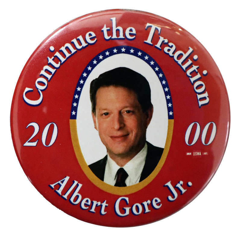 Round, red button with a color photograph of Al Gore. White text reads "Continue the Tradition 2000 Albert Gore Jr."