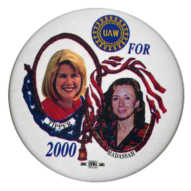 Round, white button with color photographs of Tipper Gore and Hadassah Lieberman. Yellow and black text reads "UAW FOR TIPPER HADASSAH 2000"