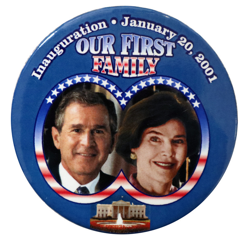 Round, blue button with color photographs of George W. and Laura Bush in a frame with the red, white, and blue stars and stripes of the US flag. Below their photographs is a color photograph of the White House. White, red, and blue text reads "Inauguration January 20, 2001 OUR FIRST FAMILY"