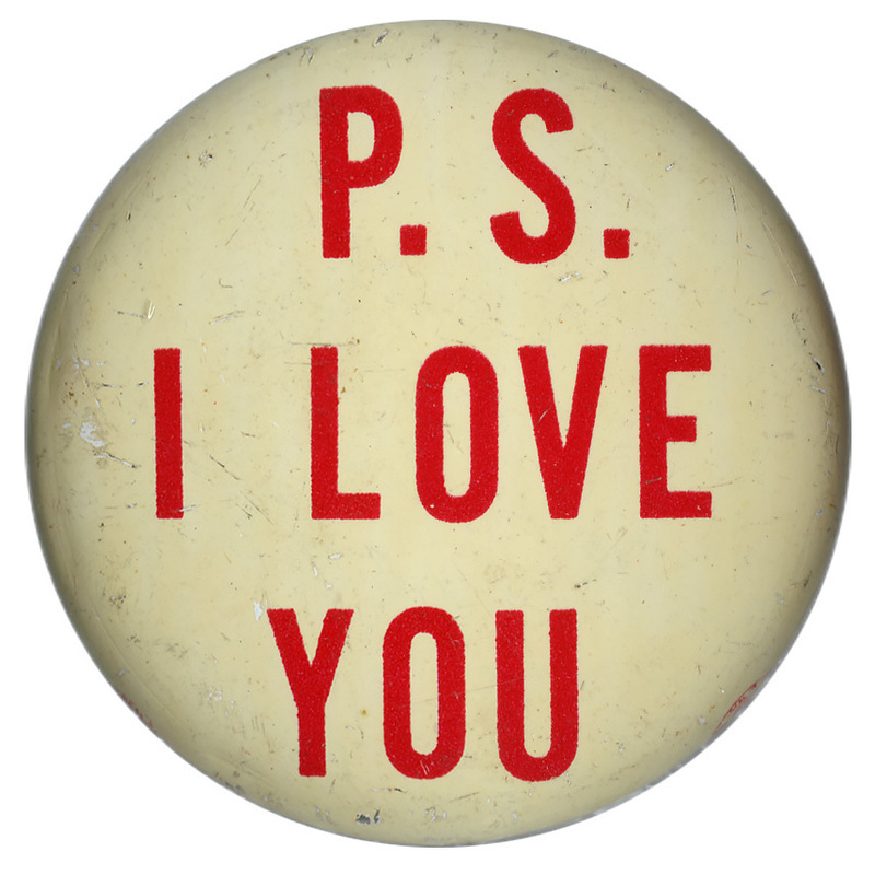 Round, off white button with red text reading "P. S. I LOVE YOU"