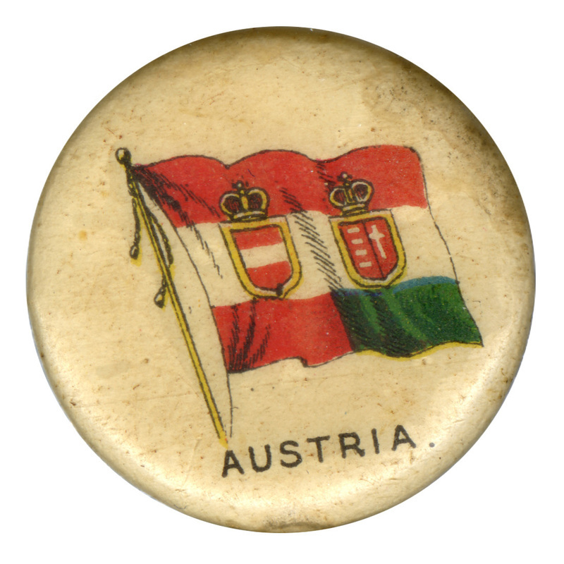 Round, white button with a color illustration of the civil ensign flag of Austria-Hungary, horizontal red, white, and green stripes with red and white shields in the center. Black text reads "AUSTRIA"