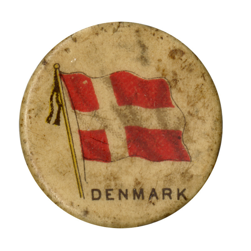 Round, white button with a color illustration of the flag of Denmark, a white cross on a red background. Black text at the bottom reads "DENMARK"