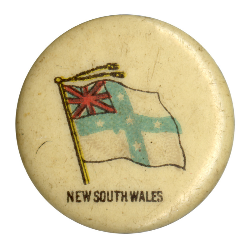 Round, white button with a color illustration of the ensign flag of the Australian state of New South Wales, a blue cross with white stars on a white background and a Union Jack in the upper left corner. Black text at the bottom reads "NEW SOUTH WALES."