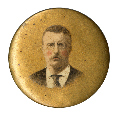 Round, gold button with a portrait of Theodore Roosevelt. 
