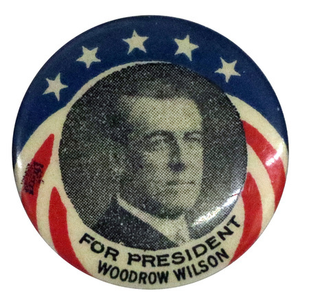Round button with a black-and-white portrait of Woodrow Wilson. It features a red, white, and blue design with stars and text reading "For President Woodrow Wilson."