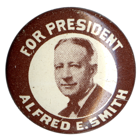 Round, white pin with a brown border and portrait of Alfred E. Smith. Bold, white text reads: "For President Alfred E. Smith". 