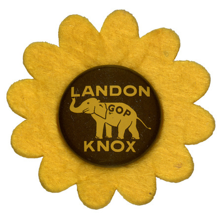 A round button with a yellow elephant with the letters "GOP" on the elephant's side. Yellow text reads "Landon Knox" on a brown background and sits atop a yellow flower-shaped felt piece.