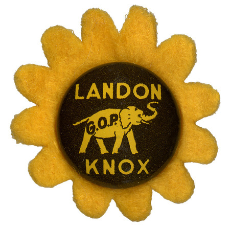 A round button with a yellow elephant with the letters "GOP" on the elephant's side. Yellow text reads "Landon Knox" on a brown background and sits atop a yellow flower-shaped felt piece.