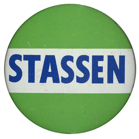 Round, light green button with a white, horizontal stripe and blue text reading "Stassen".