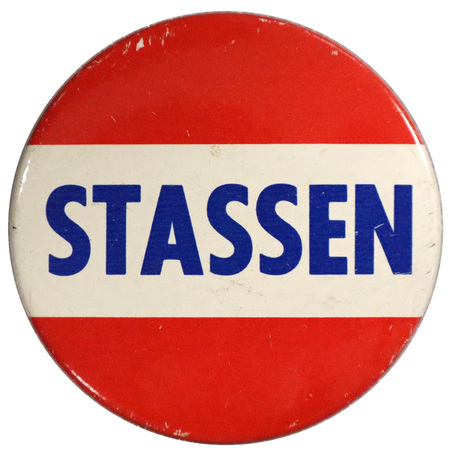 Round, red pin with a white horizontal stripe across the center. Across the white stripe is bold, blue text reading "Stassen". 