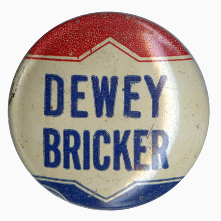 Round, white button with red and blue decorative elements. Blue text reads "Dewey Bricker". 
