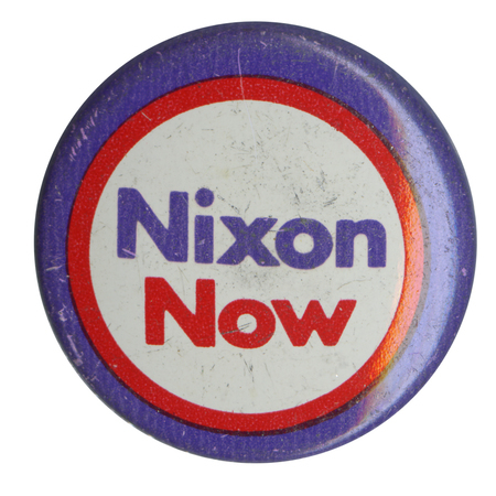 Round, white button with a blue and red border. Blue and red text reads "Nixon Now" at the center. 