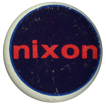 Round, dark blue button with a white border. Red text reads "nixon" at the center. 