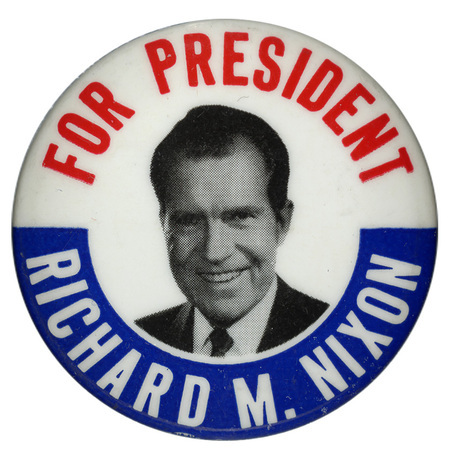 Round, white button with a blue border at the bottom, and a grayscale portrait of Richard M. Nixon. Red and white text encircling the portrait reads "For President Richard M. Nixon". 