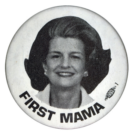 Round, white button with a black and white portrait of Betty Ford. Black text reads "FIRST MAMA"