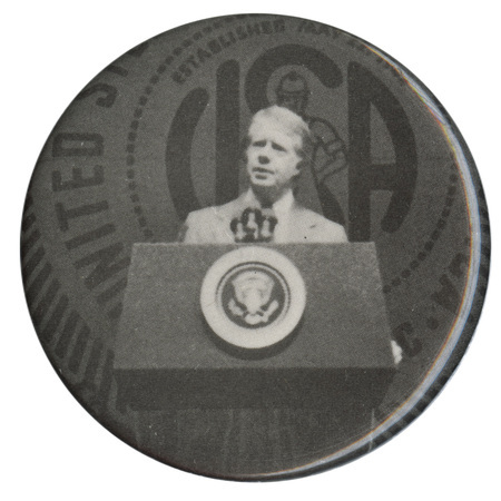 Round button with a black and white photograph of Jimmy Carter speaking at a podium.