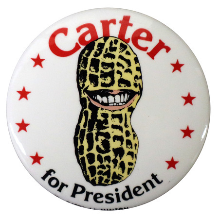Round, white button with a color drawing of a peanut with a smiling mouth, surrounded by red stars. Red and black text reads "Carter for President"