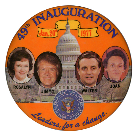 Round, orange button with color photographs of Rosalynn Carter, Jimmy Carter, Walter Mondale, and Joan Mondale, as well as the Seal of the President, against a color photograph of the US Capitol building. Blue and red text reads "49th INAUGURATION Jan. 20th 1977 Leaders, for a change"