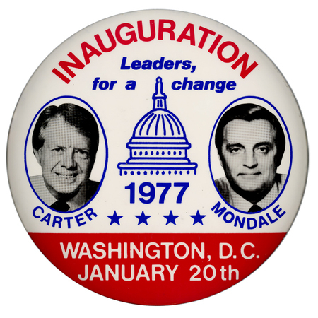 Round, white and red button with black and white photographs of Jimmy Carter and Walter Mondale within blue-outlined circles. A blue line drawing of the US Capitol building sits between the two photographs. Red and blue text reads "INAUGURATION Leaders, for a change 1977 WASHINGTON, D.C. JANUARY 20th"