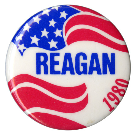 Round, white button with US flag decorations. Blue and red text reads "REAGAN 1980"