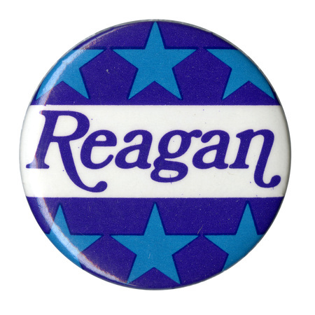 Round button with bands of light blue stars on a dark blue background. Blue text on a white band in the middle reads "Reagan"