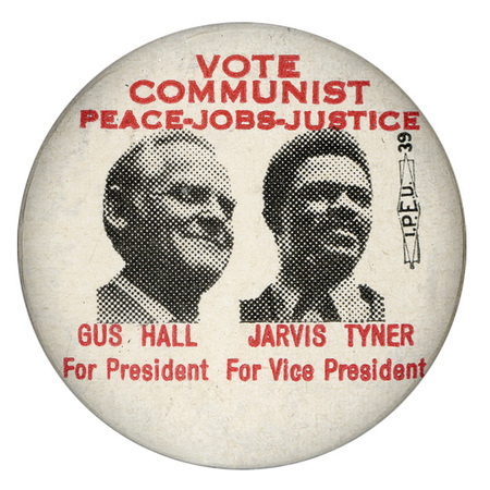 Round, white button with black and white portraits of Gus Hall and Jarvis Tyner. Red text reads "Vote Communist, Peace-Jobs-Justice, Gus Hall For President, Jarvis Tyner for Vice President."