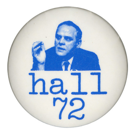 Round, white button with a blue portrait of Gus Hall. Blue text reads "hall 72."