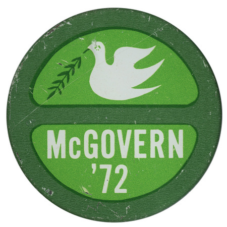 Round, green button with a drawing of a white dove with a peace sign on its head, holding a darker green olive branch. White text in the bottom half reads "McGOVERN '72"