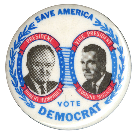 Round, white button with black and white portraits of Hubert Humphrey and Edmund Muskie surrounded by star and leaf decorations. Blue and white text reads "SAVE AMERICA PRESIDENT HUBERT HUMPHREY VICE PRESIDENT EDMUND MUSKIE VOTE DEMOCRAT"